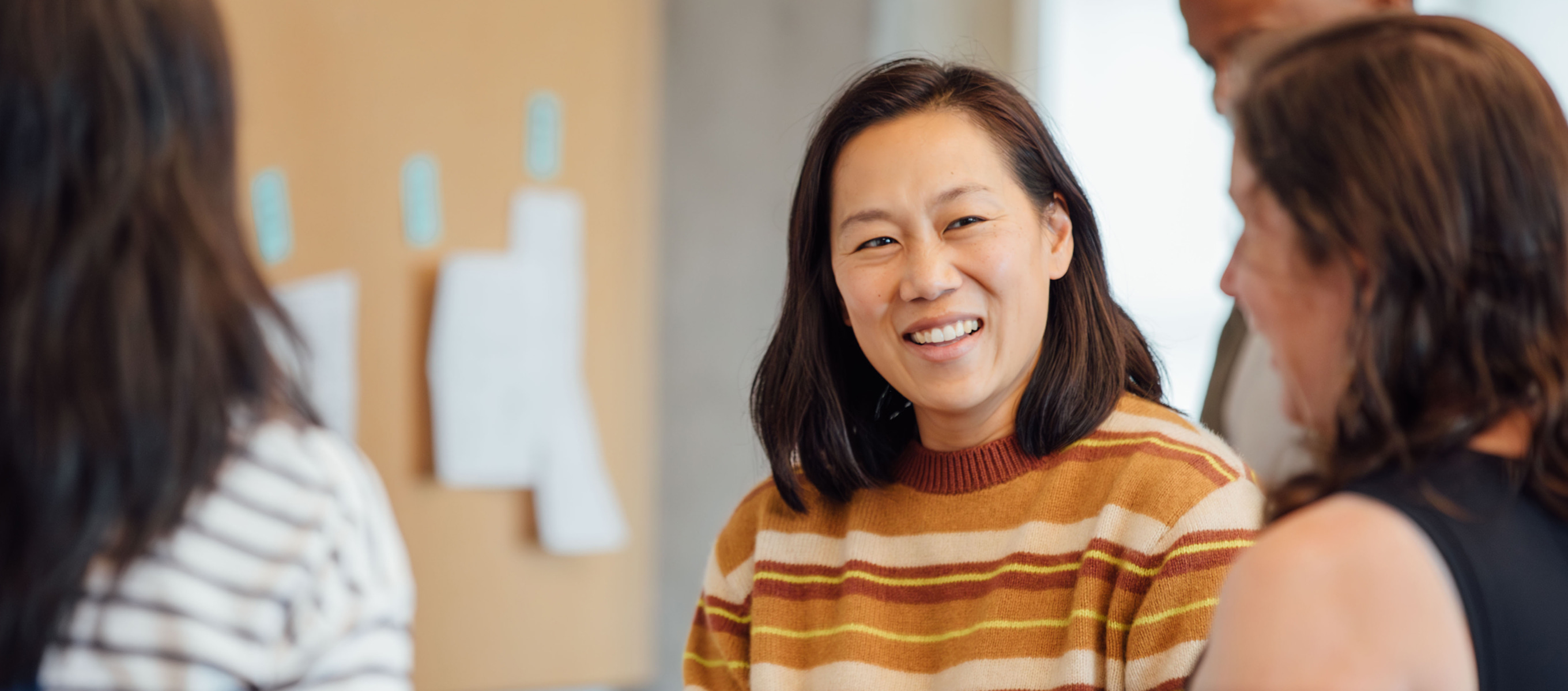 Priscilla Chan smiling during a conversation with others in an office setting