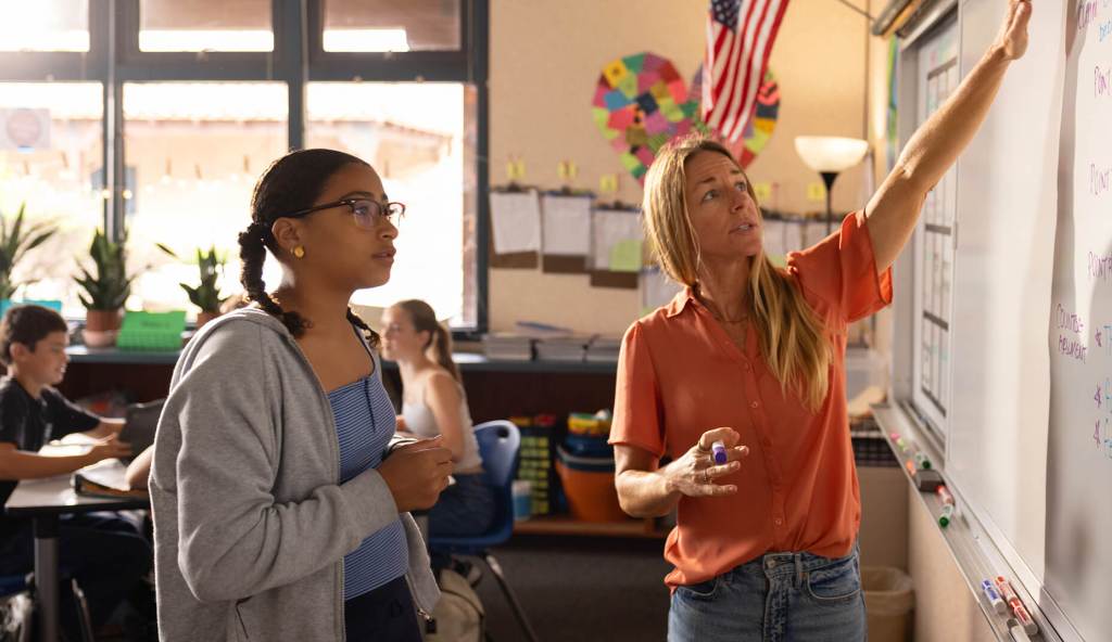 Teacher and student reviewing a lesson written on a classroom whiteboard